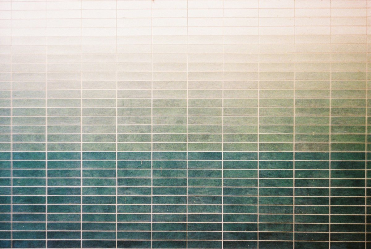 Close-up of teal-green glazed wall tiles graduating from pale to deep